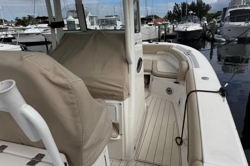 Slide: The Image of 2022 NauticStar 28 XS boat docked, featuring beige seating and covered console. - 9