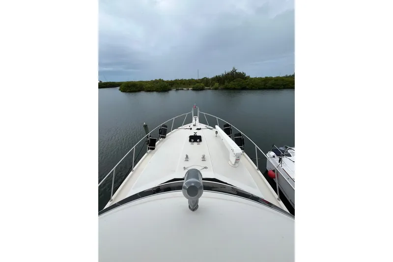 Slide: The Image of 1989 Californian 45 Motor Yacht on calm water, surrounded by lush greenery. - 6