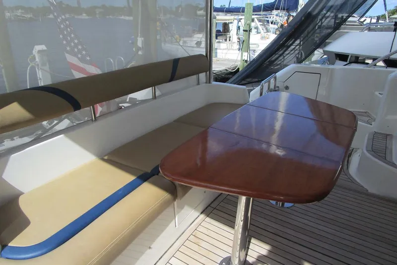 Slide: The Image of Flybridge seating area on 2006 Neptunus 56 yacht with wooden table and cushioned bench. - 46