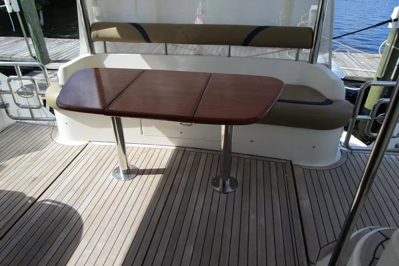 Slide: The Image of Flybridge seating area on 2006 Neptunus 56 yacht with wooden table and cushioned bench. - 43