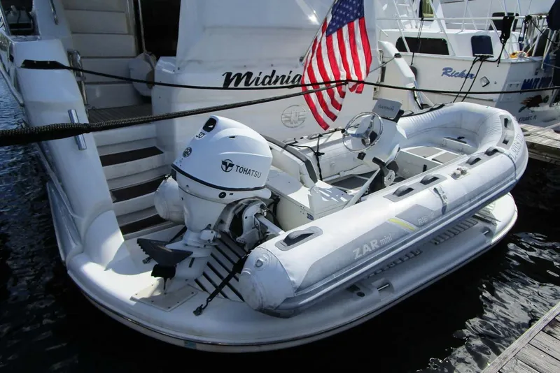 Slide: The Image of 2006 Neptunus 56 Flybridge yacht with inflatable dinghy and Tohatsu outboard motor. - 84