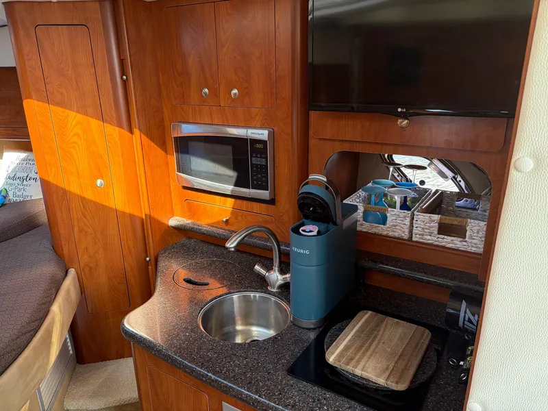 Slide: The Image of The galley of a 2013 Rinker 310 Express with a microwave, sink, and coffee maker. - 13