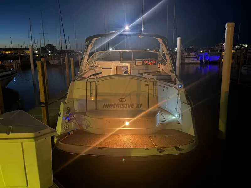 Slide: The Image of 2013 Rinker 310 Express at night in a marina, softly illuminated by lights. - 4