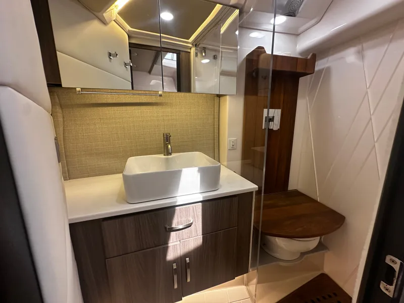 Slide: The Image of Bathroom with modern sink, wooden cabinets, and toilet in a Regal 36 Grande Coupe boat. - 12