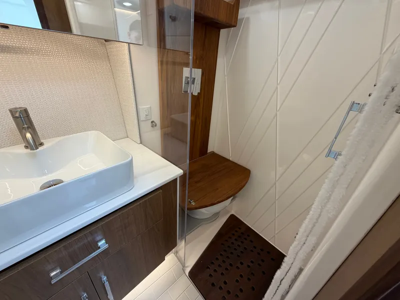 Slide: The Image of The 2027 Regal 36 Grande Coupe bathroom features a modern sink, wood accents, and a shower area. - 16