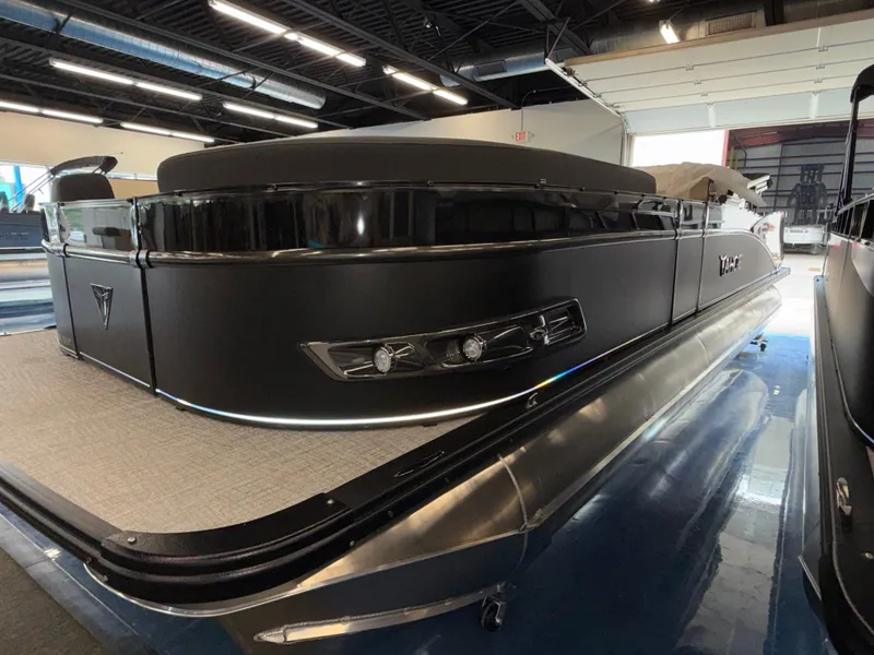 Slide: The Image of A sleek, modern pontoon boat with a black hull and silver details in a showroom. - 20