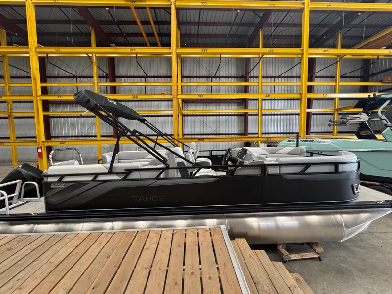 Slide: The Image of A black pontoon boat sits on a wooden dock inside a warehouse. - 1
