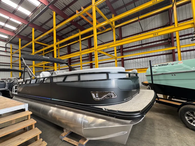 The Image of A modern pontoon boat with a gray hull and black accents, stored in a warehouse. - 0