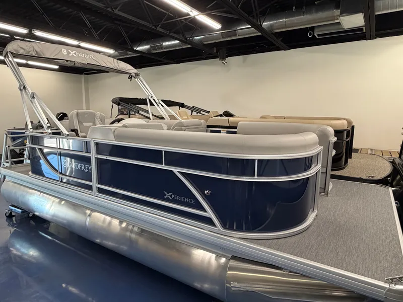Slide: The Image of The image shows a 2027 Godfrey EX 1880 Cruise pontoon boat in a showroom. - 2