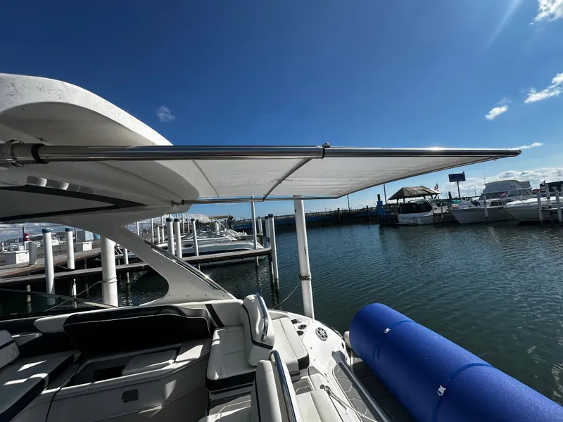 Slide: The Image of A 2023 Regal 2800 Bowrider docked. It features a retractable sunshade and blue fenders. - 8