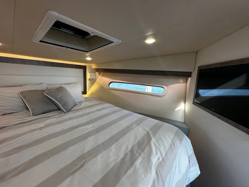Slide: The Image of Cabin of the 2022 Regal 38 Grande Coupe with a cozy bed and a window overlooking the water. - 15