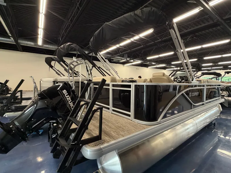 The Image of A modern pontoon boat with a black Suzuki outboard motor in a showroom. - 0