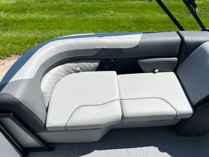 Slide: The Image of The image shows a sleek, cushioned seating area on a boat, surrounded by green grass. - 11
