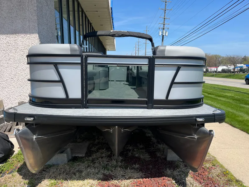 Slide: The Image of A modern pontoon boat with a gray hull and black accents, parked beside a building. - 10