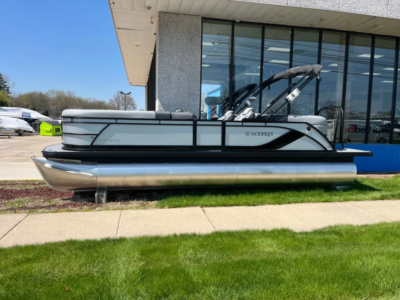 The Image of A 2026 Godfrey SW 2286 SBC pontoon boat is parked on grass in front of a building. - 0