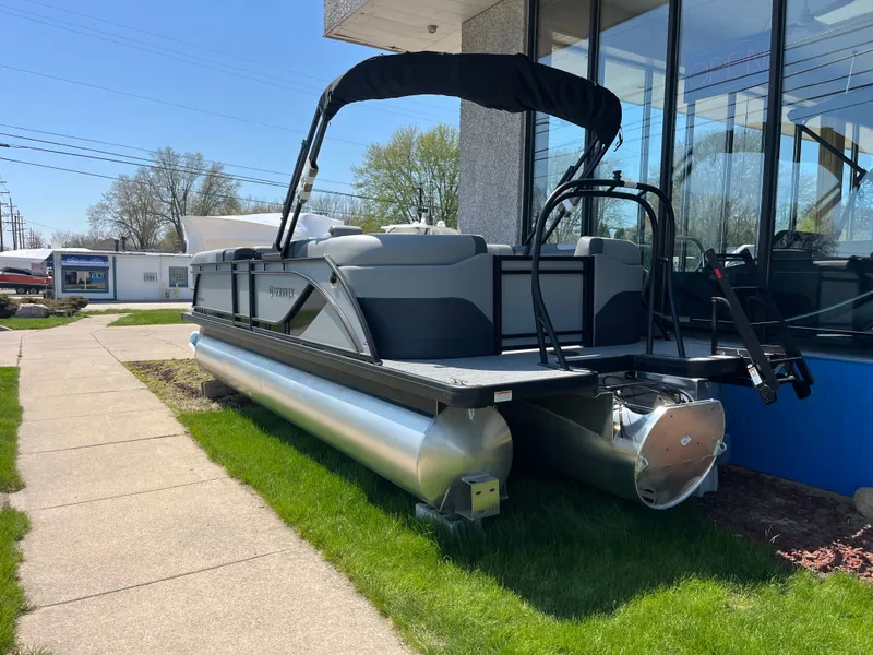 Slide: The Image of A modern pontoon boat with a black sunshade sits on green grass next to a building. - 2