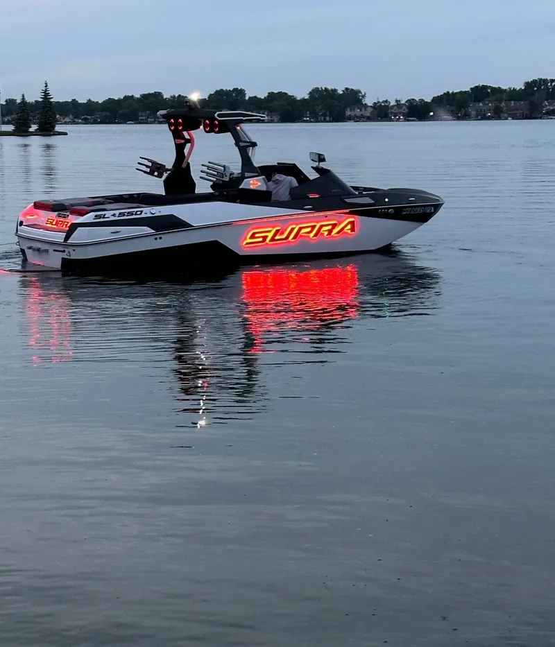 Slide: The Image of A 2022 Skiers Choice SL 550 boat with glowing signage on calm water. - 17