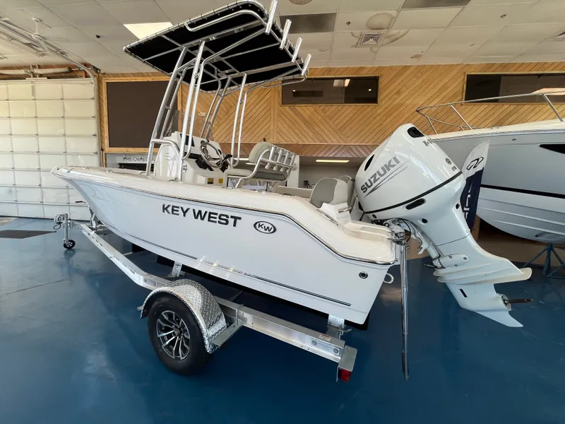 Slide: The Image of A 2026 Key West 189 FS boat with a Suzuki outboard motor in a showroom. - 1