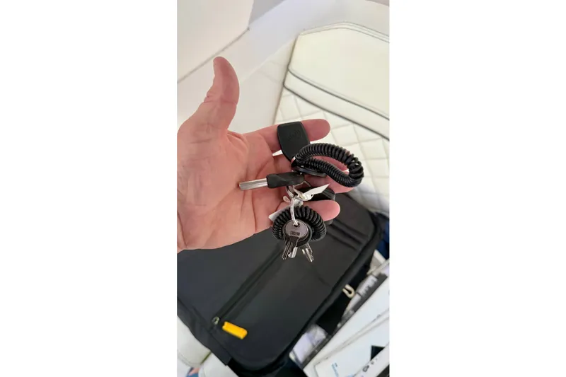 Slide: The Image of Hand holding keys for 2020 Intrepid 345 Nomad SE boat, with coiled keychain. - 43