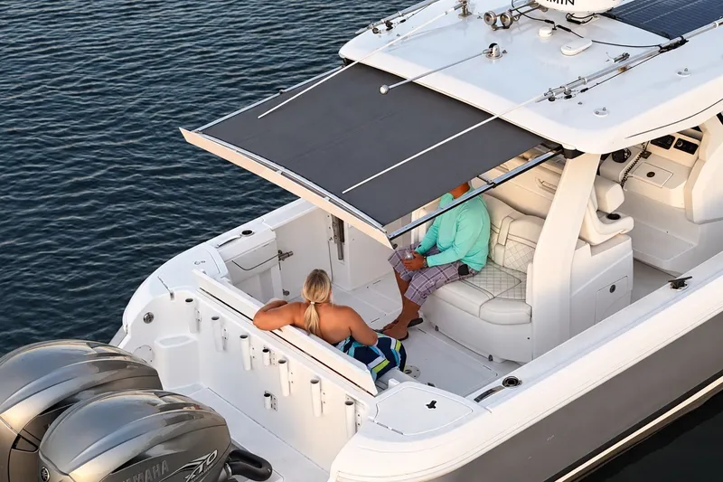 Slide: The Image of 2020 Intrepid 345 Nomad SE boat with passengers under retractable canopy on water. - 19