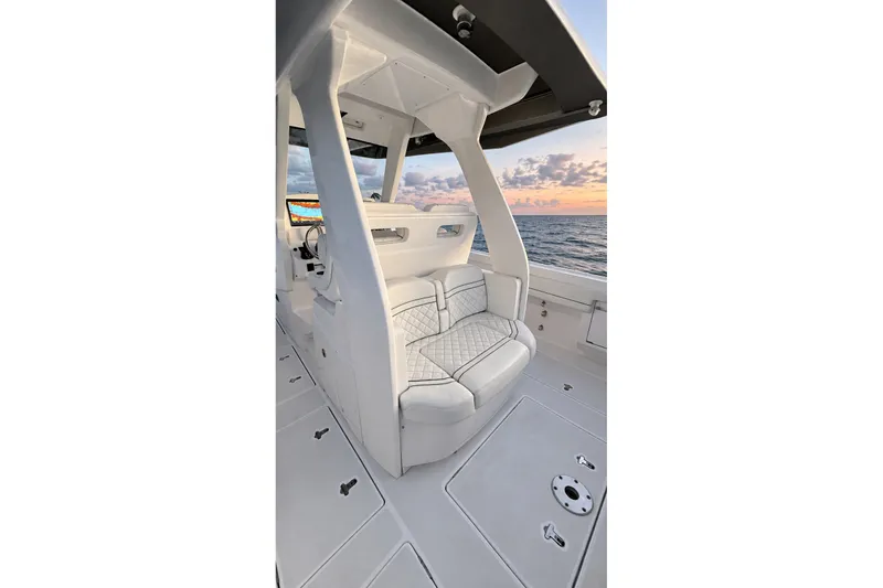 Slide: The Image of 2020 Intrepid 345 Nomad SE boat interior with cushioned seating, ocean view at sunset. - 20