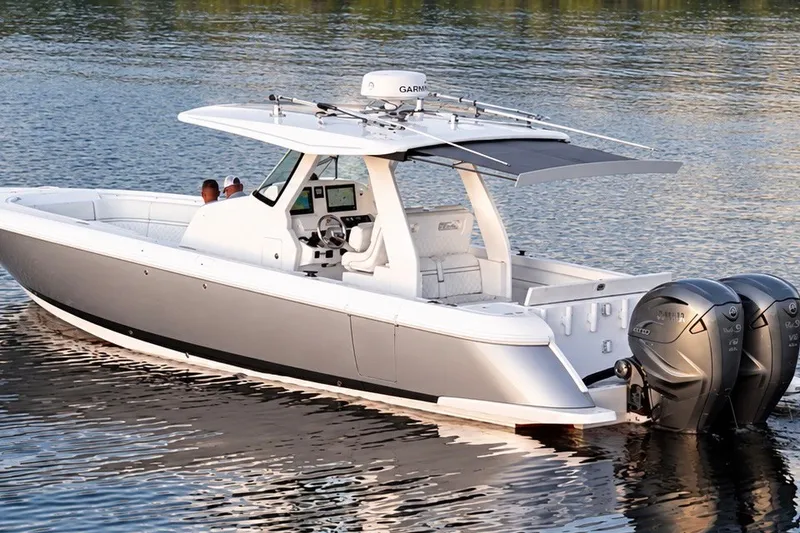 Slide: The Image of 2020 Intrepid 345 Nomad SE boat on calm water with dual outboard engines. - 25