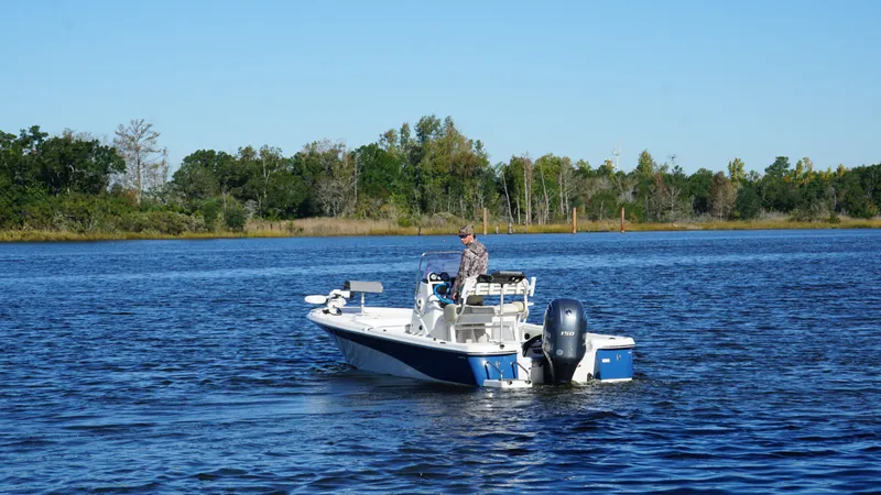 Slide: The Image of A man navigates a blue and white boat on calm waters, surrounded by trees. - 8
