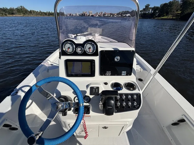 Slide: The Image of The image shows the helm of a 2022 NauticStar 215 XTS boat on calm waters. - 11