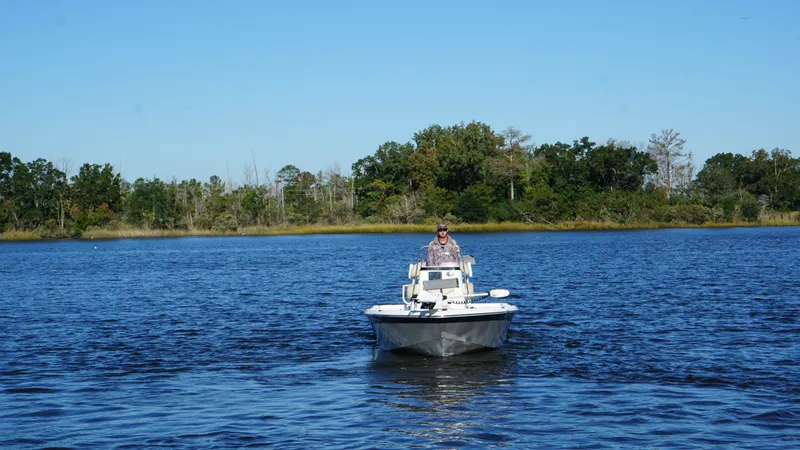 Slide: The Image of A man navigates a NauticStar 215 XTS boat on a calm lake. - 4