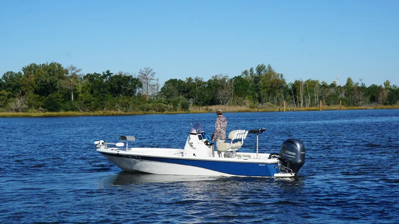 Slide: The Image of A man stands on a blue and white boat on a calm lake. - 7