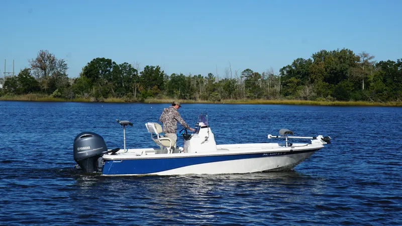 Slide: The Image of An angler navigates a blue and white boat on a calm lake. - 2