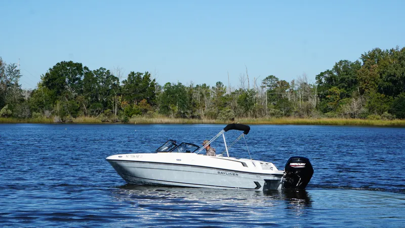 Slide: The Image of 2025 Bayliner VR4 Bowrider OB on a calm lake with a wooded shoreline in the background. - 5