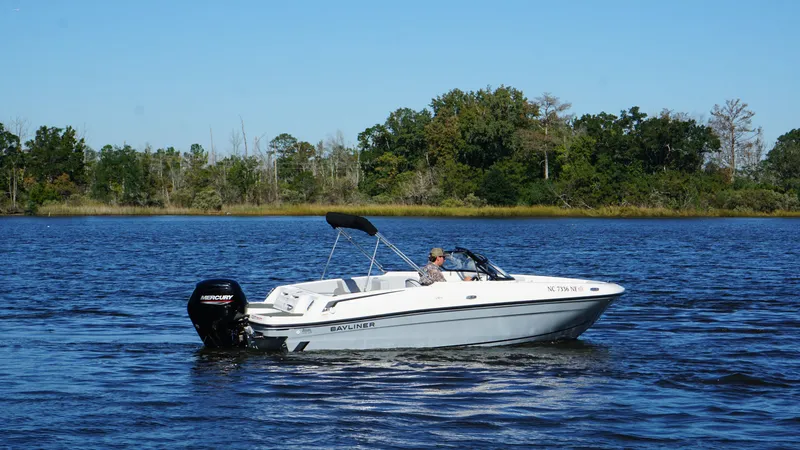 Slide: The Image of Bayliner VR4 Bowrider OB 2025 on a calm lake with a wooded shoreline in the background. - 6