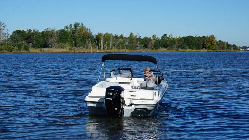 Slide: The Image of A 2025 Bayliner VR4 Bowrider OB on calm water with a wooded shoreline. - 7