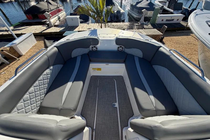 Slide: The Image of 2024 NauticStar 223 DC Deck boat interior with gray seating at marina. - 17