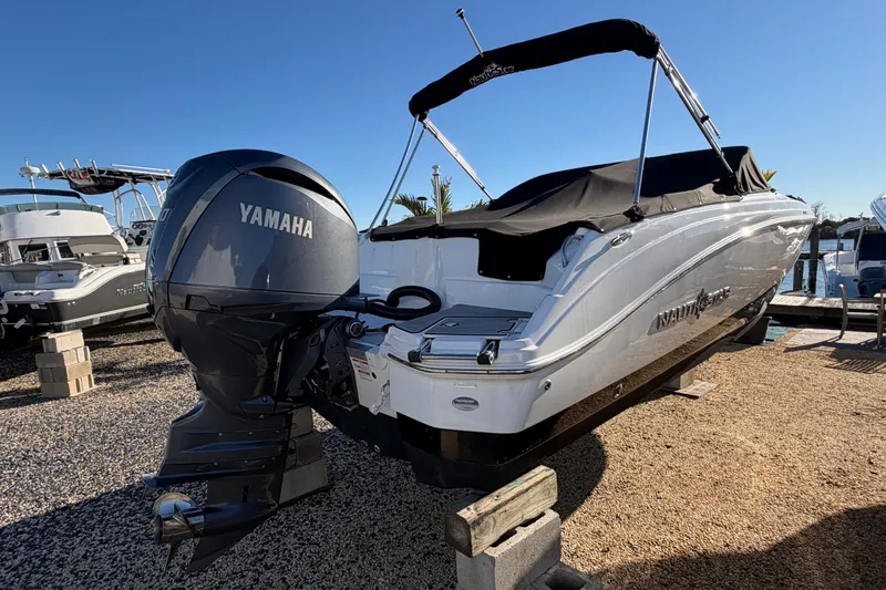 Slide: The Image of 2024 NauticStar 223 DC Deck boat with Yamaha engine, covered and docked outdoors. - 3