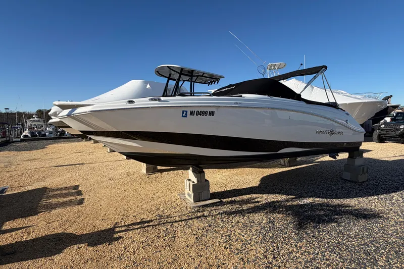 Slide: The Image of 2024 NauticStar 223 DC Deck boat displayed on stands in a sunny marina. - 4