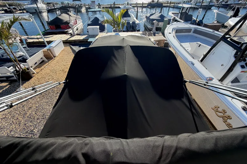 Slide: The Image of 2024 NauticStar 223 DC Deck boat covered at marina, surrounded by other boats. - 27