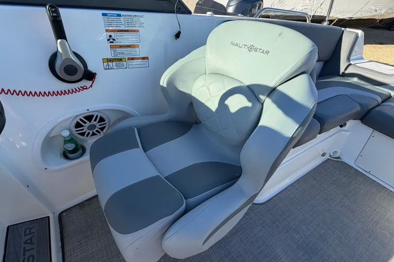 Slide: The Image of Captain's seat on 2024 NauticStar 223 DC Deck boat, featuring ergonomic design and control panel. - 11