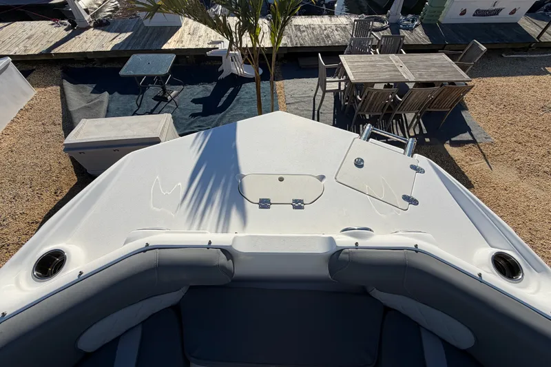 Slide: The Image of 2024 NauticStar 223 DC Deck boat bow with seating and dockside view. - 18
