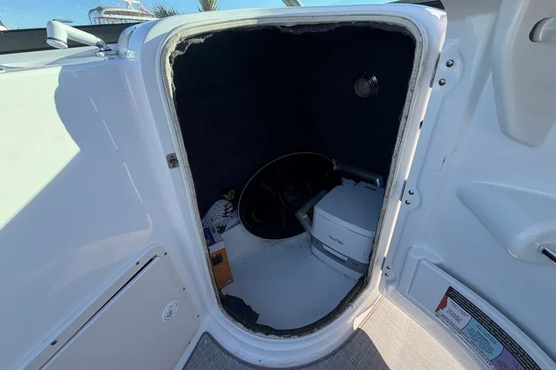 Slide: The Image of 2024 NauticStar 223 DC Deck boat storage compartment with portable toilet and accessories. - 15