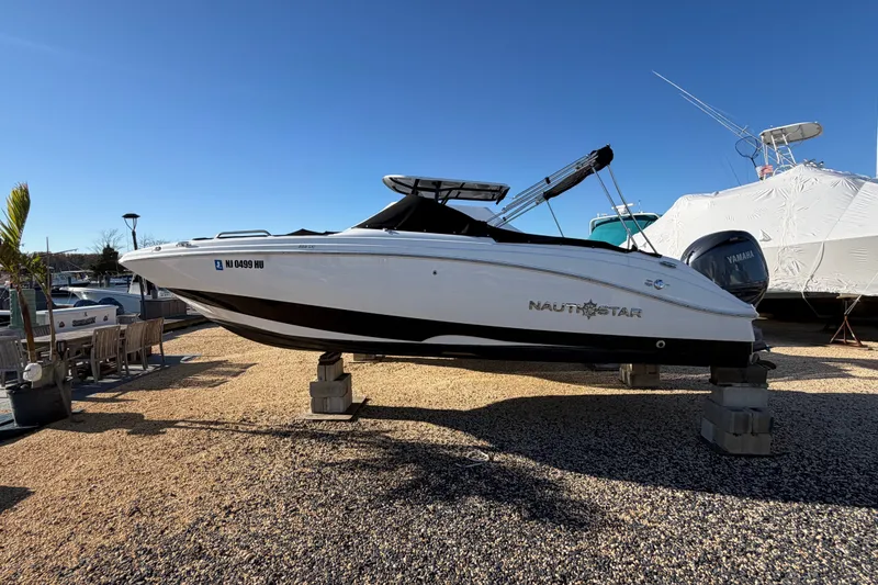 Slide: The Image of 2024 NauticStar 223 DC Deck boat displayed on blocks in a marina setting. - 1