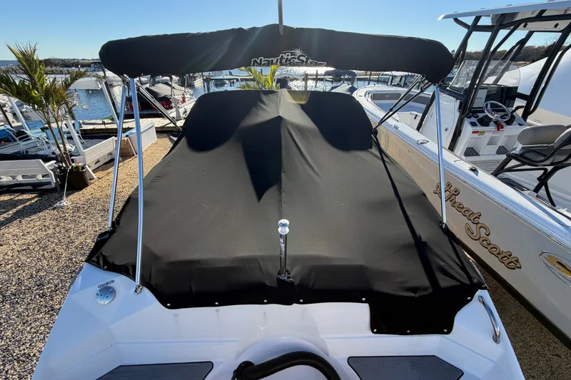 Slide: The Image of 2024 NauticStar 223 DC Deck boat with black cover, docked at marina. - 26