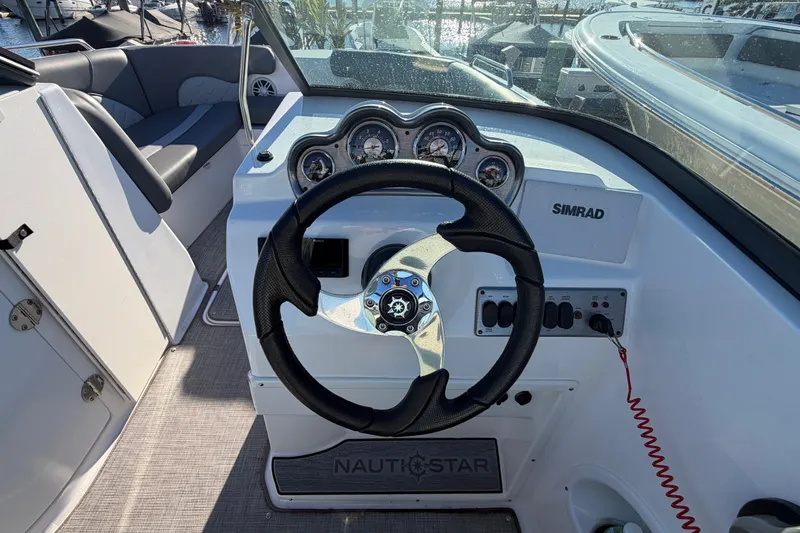 Slide: The Image of 2024 NauticStar 223 DC Deck boat helm with steering wheel and instrument panel. - 13