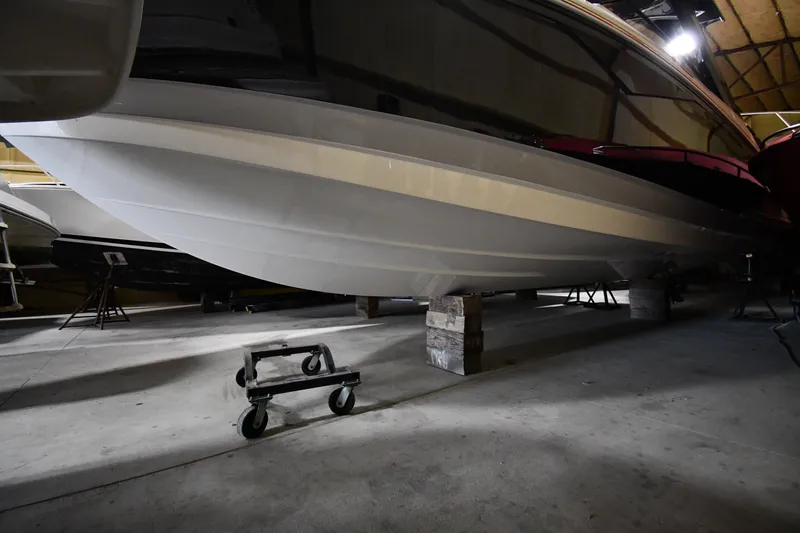 Slide: The Image of 2024 Cobalt A29 boat hull in storage, supported by blocks in a dimly lit warehouse. - 32
