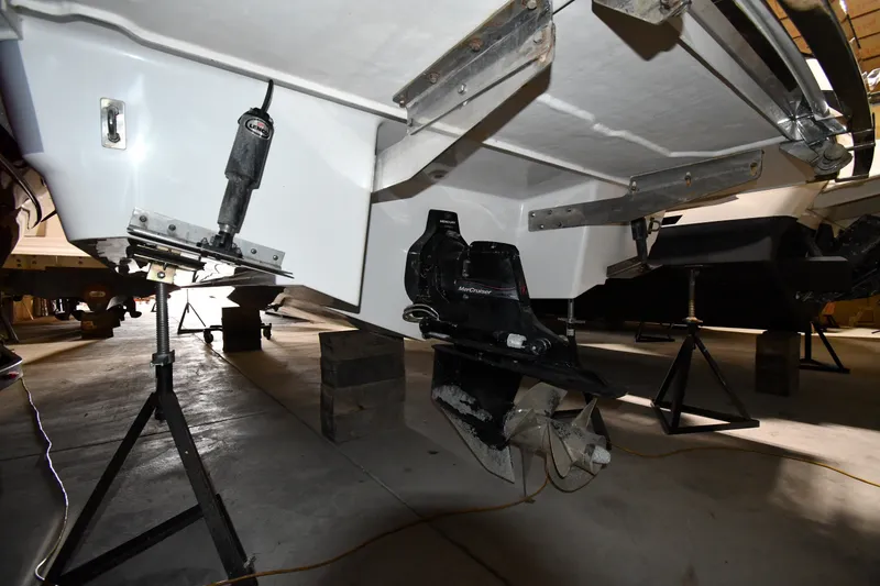 Slide: The Image of 2024 Cobalt A29 boat underside with propeller and support stands in a garage. - 34