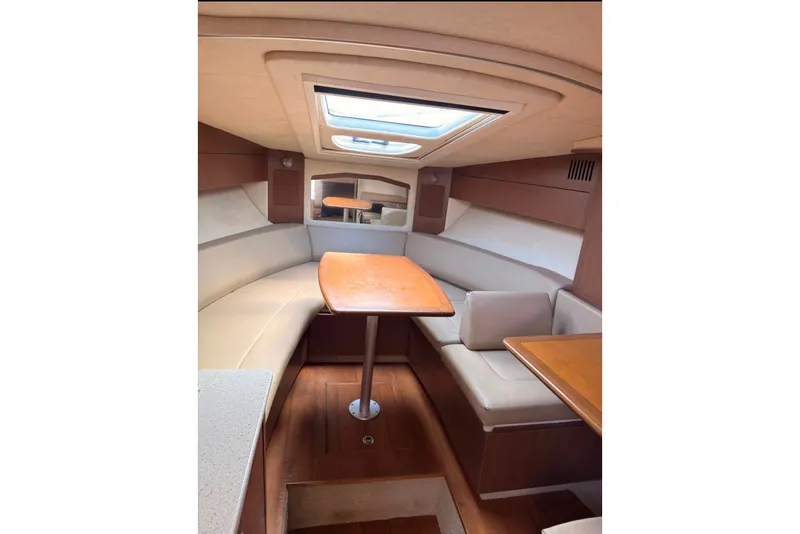 Slide: The Image of 2013 Sea Ray Sundancer 310 cabin interior with seating and table, featuring a skylight. - 9