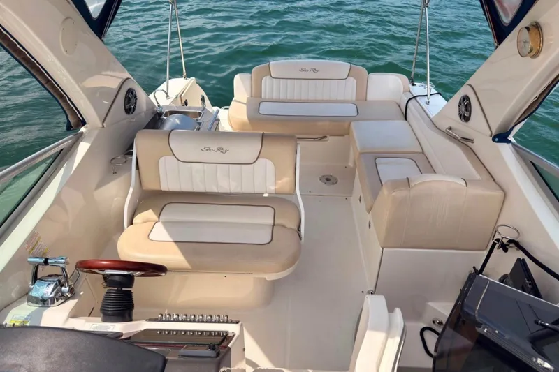 Slide: The Image of 2013 Sea Ray Sundancer 310 boat interior with beige seating, steering wheel, and ocean backdrop. - 6