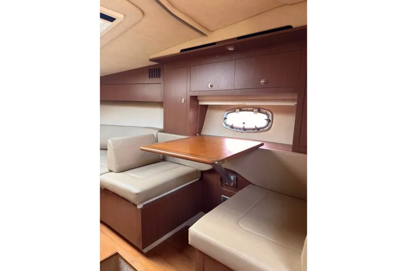 Slide: The Image of Interior of 2013 Sea Ray Sundancer 310, featuring a cozy dining area with wood finish. - 8
