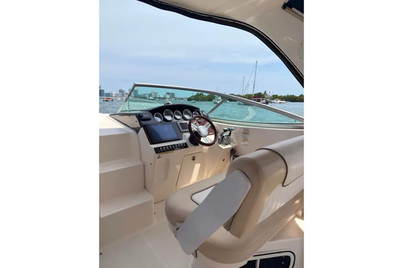Slide: The Image of 2013 Sea Ray Sundancer 310 helm with steering wheel and navigation controls, overlooking water. - 5